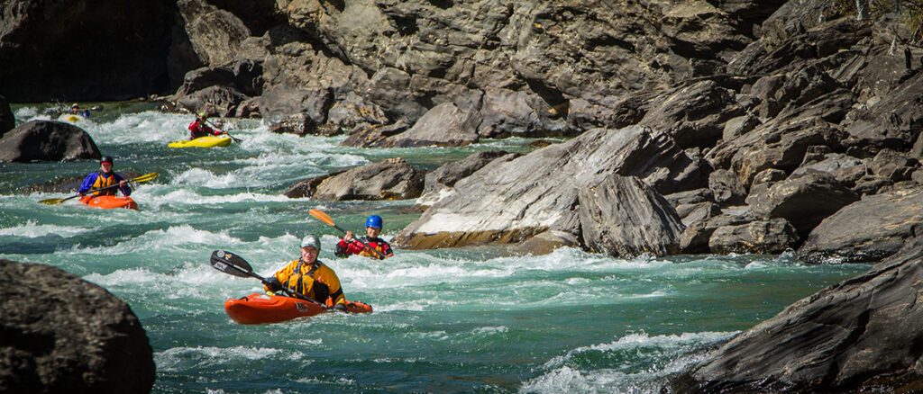 Four Kayakers paddling white water on lower Paro Chu River